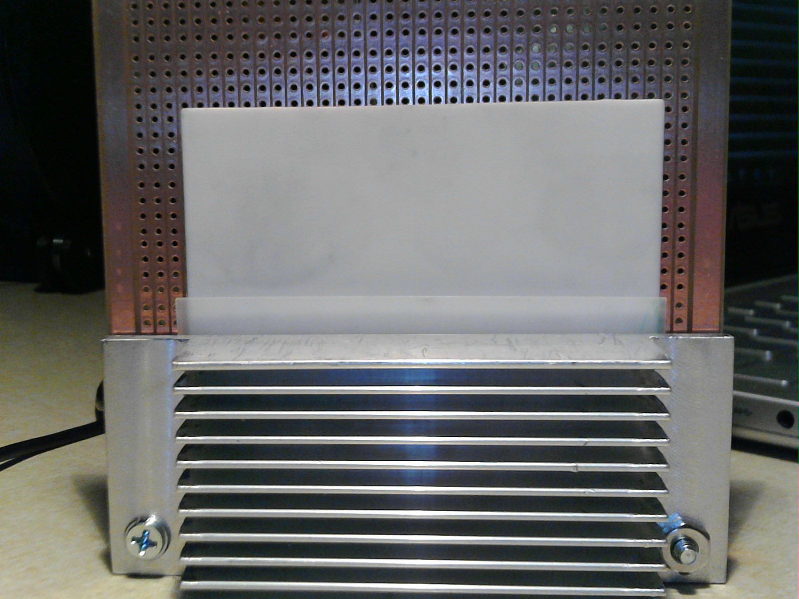 in the foreground, the aluminum heat sink, and left and right, the 6-32" clamping screws are visible, as is the white aluminum oxide substrate, and silicone pad. In the background, the strip board fills the space and provides electrical contact to the silicon carbide filament.