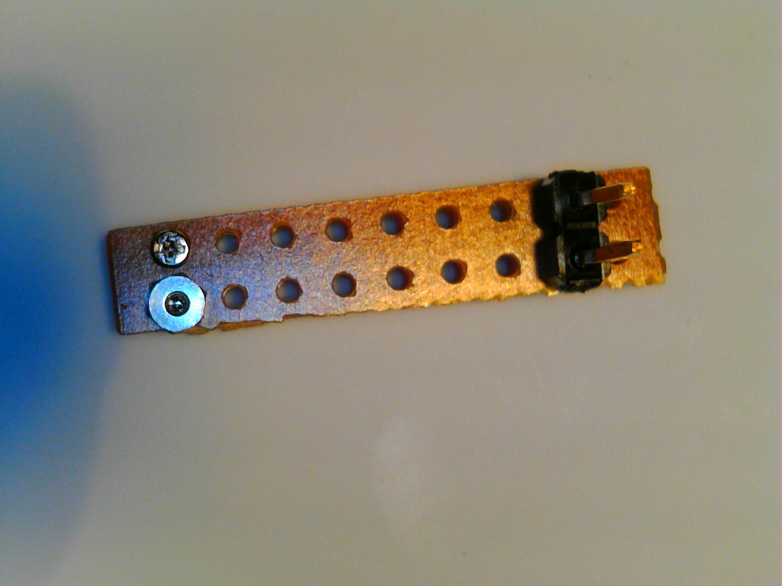 a view of the generation 2 print head from the front, showing the two clamp screws, the unmetallized back side of the strip board that makes up the body, and the two, 0.1" header pins for connection to power and ground, for the single heater in this device