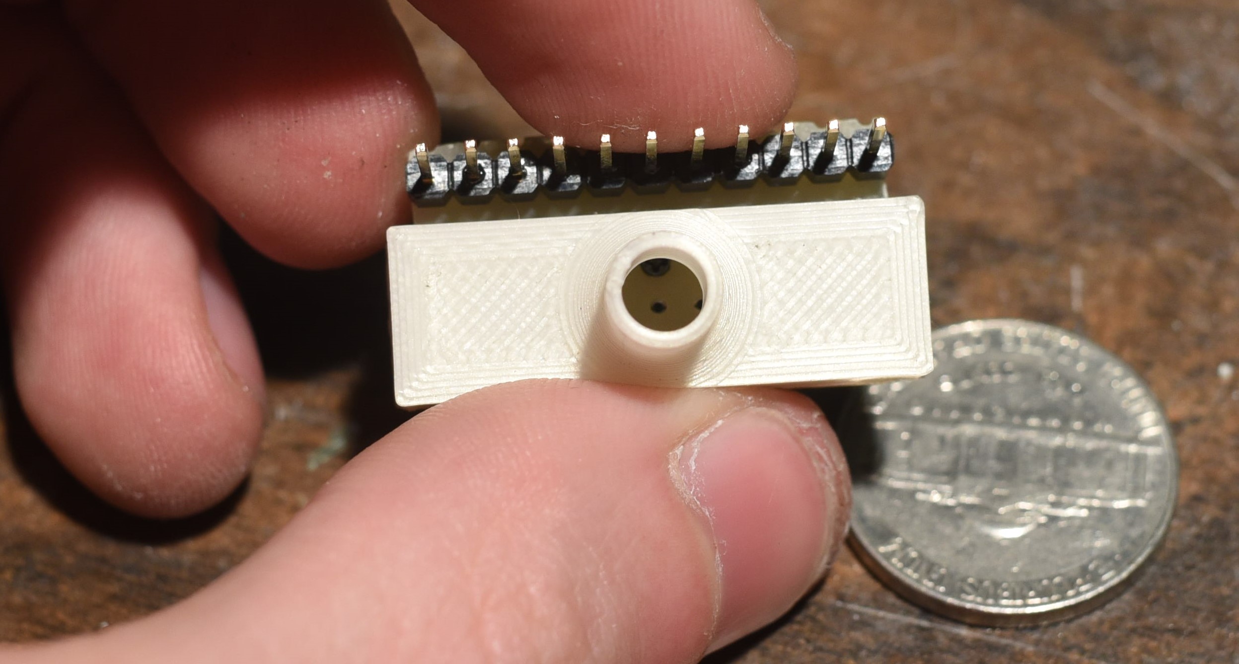 A view of the 3d printed manifold, which has been superglued in place. Looking inside the hole in the manifold, the top of one of the black oxide screws holding the nozzle plate to the strip board is visible. These screws also act to clamp the filament between the perfboard nozzle plate and stripboard connector plate.